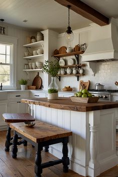 a kitchen with white cabinets and wooden floors, an island bench in the middle is surrounded by pots and pans