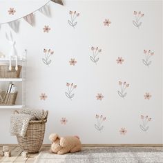 a baby's room with flowers on the wall and a teddy bear sitting in front of it