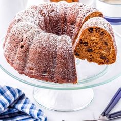 a bundt cake with powdered sugar and raisins is on a glass platter