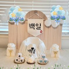 baby shower items displayed in front of a wooden backdrop with balloons and flowers on it