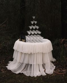 a table with a cake on it in the middle of a forest filled with trees