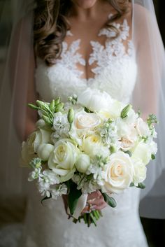 a bride holding a bouquet of white flowers