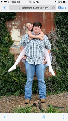 a man and woman standing in front of a wall with ivy growing on it's sides