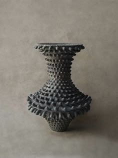 a black vase sitting on top of a white table next to a gray wall and floor