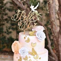 a wedding cake with butterflies and roses on top is decorated in gold, white and pink