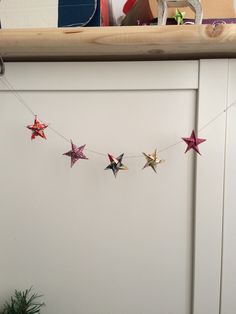 a string of star garland hanging from a kitchen cabinet with christmas decorations in the background