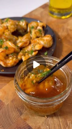 some food is on a wooden table with chopsticks in the bowl and sauce