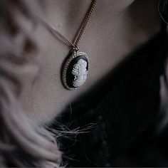 a close up of a person wearing a necklace with a medallion on it's neck