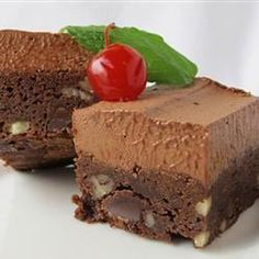 a piece of chocolate cake with a cherry on top and one slice cut in half