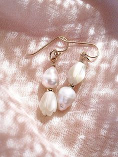 These asymmetrical carved Pikake and Baroque Pearl Earrings make beautiful simple statements. Seemingly plucked straight from the ocean, the luminous, organic white pearls sway and illuminate in the light. Wear these unique pearl, pikake, and gold earrings for a modern upgrade.✦ DETAILS ✦✧ Name: Huali - (hoo A lee) - Pure, bright, gleaming.✧ 14kt Gold Filled.✧ Genuine Freshwater Baroque Pearls.✧ Carved Mother of Pearl Pikake Flowers.✧ All Ke Aloha Jewelry pieces come packaged thoughtfully, beaut Delicate Baroque Pearl White Earrings, Handmade Delicate Baroque Pearl Earrings, White Baroque Pearl Earrings With Pearl Charm, White Baroque Pearl Earrings As A Gift, Delicate Pear-shaped Earrings For Pierced Ears, White Pearl Charm Earrings, Graceful White Pearl Charm Earrings, Graceful White Pearl Earrings With Charm, Delicate Baroque Pearl Earrings