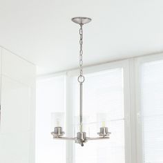 a chandelier hanging from the ceiling in a dining room with white walls and windows