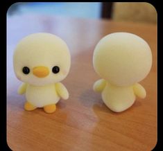 two small yellow and white toys sitting on top of a wooden table next to each other