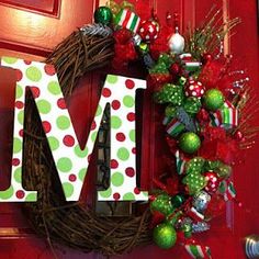 a christmas wreath with the letter m hanging on it's front door, decorated with green and red ornaments