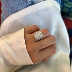 a woman's hand with a diamond ring on top of her left arm, wearing a white shirt and blue jeans