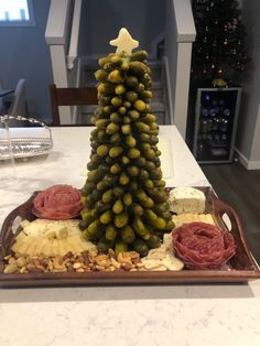 a christmas tree made out of olives and cheese on a platter at a table