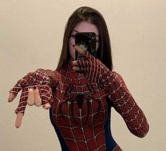 a woman is taking a selfie with her cell phone wearing a spiderman costume