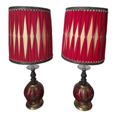 two lamps with red shades on them sitting next to each other