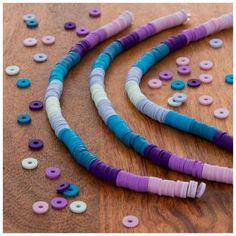 several different colored beads on a wooden surface