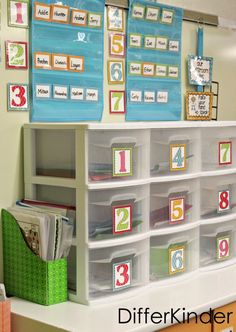 a classroom desk with lots of bins and labels on the wall, along with other items