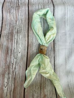 a light green scarf tied to a wooden table with wood planks in the background