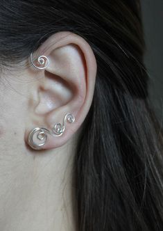 a woman's ear with two silver spirals on it