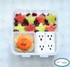 a plastic container filled with dices, fruit and other food on top of a table