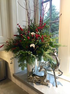 a silver vase filled with red berries and greenery