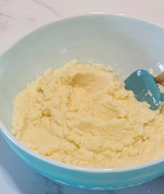 a blue bowl filled with mashed potatoes and a wooden spoon