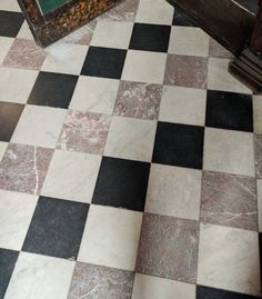 a black and white checkered floor with an old wooden door in the corner next to it