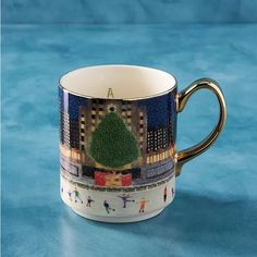 a coffee cup with a christmas tree on the front and bottom is sitting on a blue surface