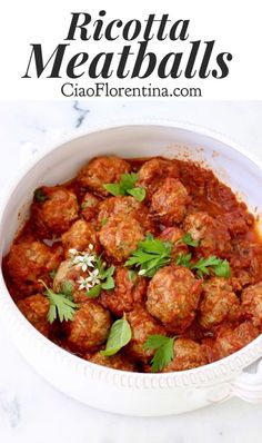 a white bowl filled with meatballs covered in sauce and garnished with parsley