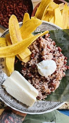 a plate with rice, beans and banana slices on it next to some other foods