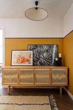 a living room with yellow walls and an art piece on top of the entertainment center