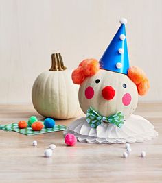 a pumpkin with a clown hat on it next to other decorations and candy candies