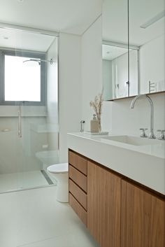 a bathroom with a sink, toilet and shower stall in the background is a white tiled floor