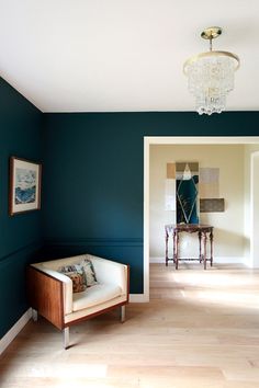 an empty room with blue walls and wooden floors, including a chair in the middle