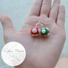 pair of mushroom earrings in hand on white background