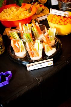 an assortment of food is displayed on a black table with purple and orange napkins