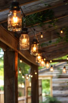 mason jar lights hanging from a pergolated covered porch with greenery on either side