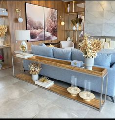 a living room with blue couches and vases filled with flowers on the coffee table