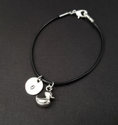 Personalized Waxed Cord Bracelet!  A three dimensional rubber duck charm on a black waxed cord makes the perfect gift for your best friend.The duck charm is made from zinc alloy and measures 12 mm by 5 mm.  The charm is reversible.  The bracelet is a waxed braided rope and measures 7.25" with a 1-2" extender (see last picture).  The lobster clasp is zinc alloy.  The black cord bracelet can be personalized with a .5" silver plated disc stamped with the initial of your choice.  Each personalized b Adjustable Black Novelty Charm Bracelet, Black Adjustable Charm Bracelet, Novelty Style, Black Novelty Bracelet Jewelry, Adjustable Black Charm Bracelet With Lobster Clasp, Adjustable Black Bracelets With Charms, Adjustable Nickel-free Black Charm Bracelet, Nickel-free Black Charm Bracelet For Gift, Nickel-free Black Charm Bracelet As Gift, Duck Bracelet