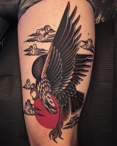 an eagle tattoo on the leg of a man with clouds and birds around it,