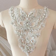 the back of a wedding dress with beading and pearls on it's neck