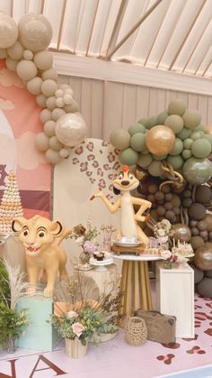 a table topped with lots of balloons and animals next to a wall covered in balloons