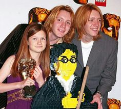 two women and a man holding legos in front of a wall with an angry bird on it