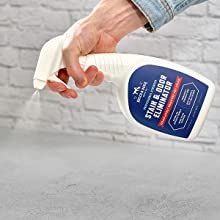 a person is using a spray bottle to clean the surface of a concrete floor in front of a brick wall