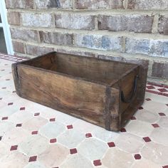 a wooden box sitting on top of a tiled floor next to a brick wall and door