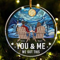 a glass ornament with two people sitting on chairs in front of a christmas tree