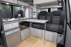 the interior of a camper with an oven, sink and table in front of it