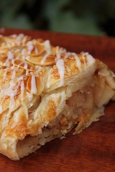 a close up of a pastry on a wooden table with icing and almonds